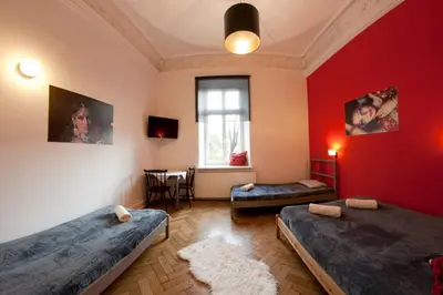 a room with two beds and a red wall at Pokoje Bagatela Stare Miasto in Kraków