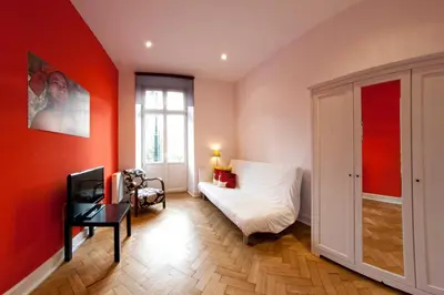 a bedroom with red walls and a bed and a chair at Pokoje Bagatela Stare Miasto in Kraków