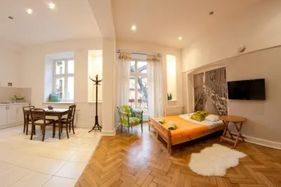 a bedroom with a bed and a table and a kitchen at Pokoje Bagatela Stare Miasto in Kraków
