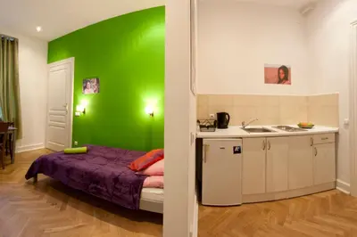 a green room with a bed and a kitchen at Pokoje Bagatela Stare Miasto in Kraków