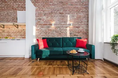 a living room with a green couch and a brick wall at Old Time Apartments in Kraków