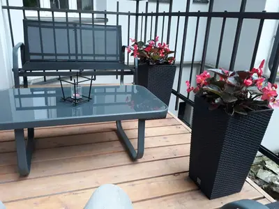 a table and chairs on a balcony with flowers at Old Time Apartments in Kraków