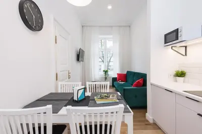 a kitchen and living room with a table and chairs at Old Time Apartments in Kraków