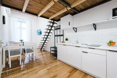 a kitchen with white cabinets and a table with chairs at Old Time Apartments in Kraków