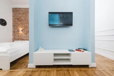a white living room with a tv on a blue wall at Old Time Apartments in Kraków