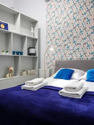 a bedroom with a large bed with a blue carpet at CracWoW Apartment in Kraków