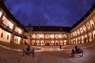 a large building with two seats in a courtyard at night at Zamek Królewski w Niepołomicach in Niepołomice