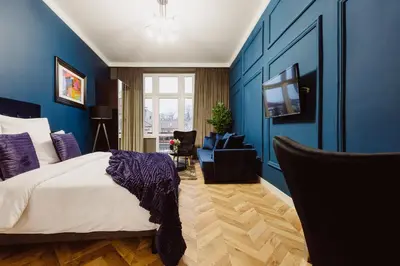 a bedroom with a bed and a blue wall at Kings City - Blich Apartment in Kraków