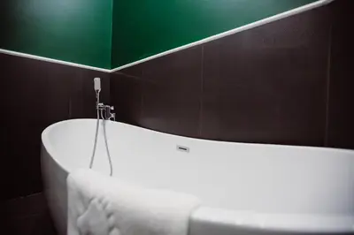 a bath tub in a bathroom with a green wall at Kings City - Blich Apartment in Kraków