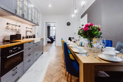 a kitchen with a long wooden table with blue chairs at Kings City - Blich Apartment in Kraków