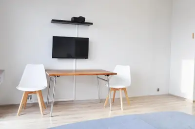 a table with two white chairs and a television on a wall at Os. 2 pułku 26 - studio by Homeprime in Kraków