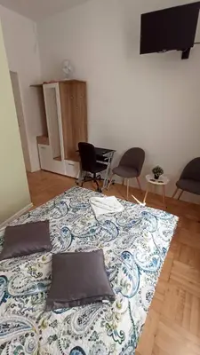 a bed in a room with two chairs and a television at Lukas Guest Rooms in Kraków