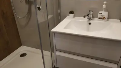 a white bathroom with a sink and a shower at Lukas Guest Rooms in Kraków