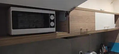 a microwave on a wooden shelf in a kitchen at Lukas Guest Rooms in Kraków