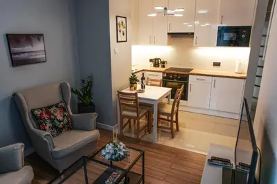 a living room and kitchen with a table and chairs at Nowe Zabłocie in Kraków