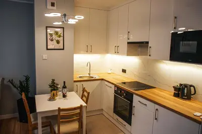 a kitchen with white cabinets and a table and a sink at Nowe Zabłocie in Kraków