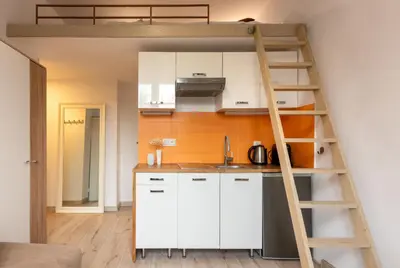 a kitchen with white cabinets and a loft bed at Solna Atelier in Kraków