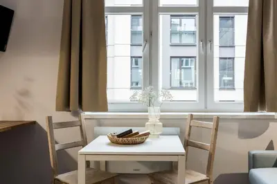 a table and chairs in a room with windows at Solna Atelier in Kraków