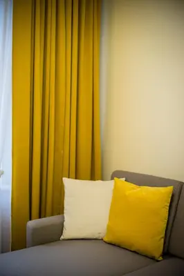a yellow pillow sitting on a couch in front of a curtain at Apartament Wietora WAWELOFTS in Kraków