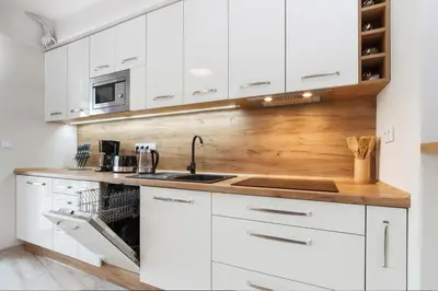 a kitchen with white cabinets and a wooden counter top at PIANISSIMO in Kraków