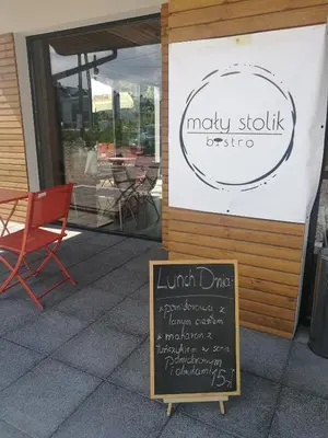 a sign in front of a restaurant with a table and chairs at Salt Mine Apartment 64m2 in Wieliczka