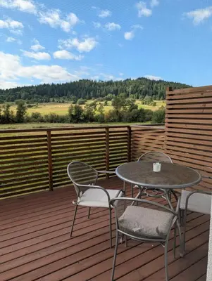 two chairs and a table on a wooden deck at Apartament Przy Potoku in Zubrzyca Górna