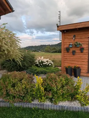 a garden with flowers and a wooden shed at Apartament Przy Potoku in Zubrzyca Górna