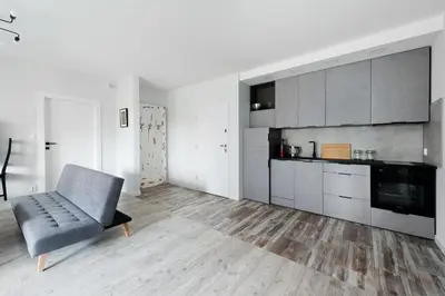 a living room with a chair and a kitchen at Ludwinowska11 Apartments in Kraków