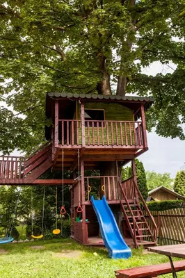 a tree house with a slide and a playground at Willa Szarotka in Rabka