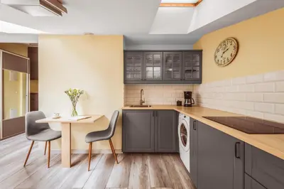 a kitchen with a table and chairs and a clock at Native Apartments Rakowicka 6 in Kraków