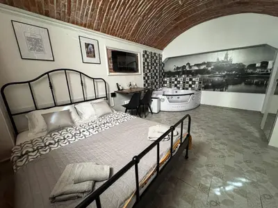 a bedroom with a bed and a table and a tub at UNDERGROUND Jacuzzi Rooms in Kraków