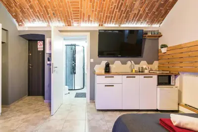 a kitchen with white cabinets and a flat screen tv at UNDERGROUND Jacuzzi Rooms in Kraków