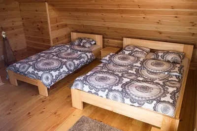two beds in a room with wooden floors at Wrzosowe Zacisze in Siepraw