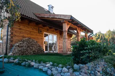 a log house with a pile of logs in front of it at Wrzosowe Zacisze in Siepraw
