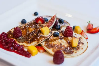 a plate of pancakes with fruit and berries at WONDER CRACOW in Kraków