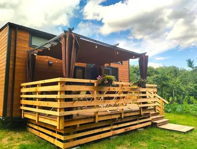 a cabin with a deck and awning on top of it at Domki Całoroczne - Tarlagowy Bór in Bebło