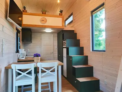 a small kitchen with a table and stools in a tiny house at Domki Całoroczne - Tarlagowy Bór in Bebło