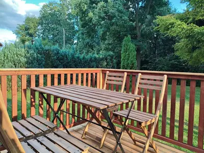 a wooden table and two chairs on a wooden deck at Domki Całoroczne - Tarlagowy Bór in Bebło
