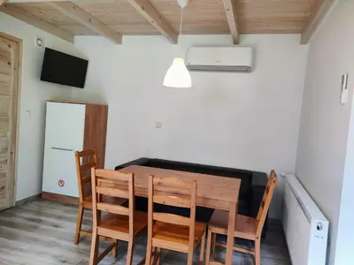a dining room with a wooden table and chairs at Domki Całoroczne - Tarlagowy Bór in Bebło