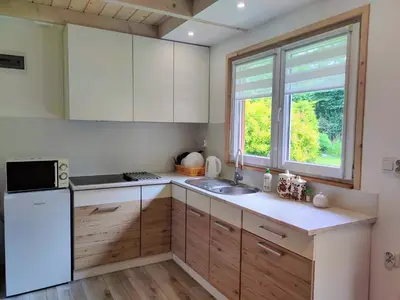 a kitchen with white cabinets and a sink and a window at Domki Całoroczne - Tarlagowy Bór in Bebło