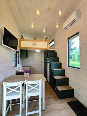 a small kitchen and dining room of a tiny house at Domki Całoroczne - Tarlagowy Bór in Bebło