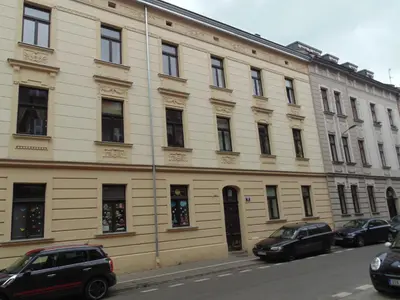 a large white building with cars parked in front of it at Apartment Lenartowicza in Kraków