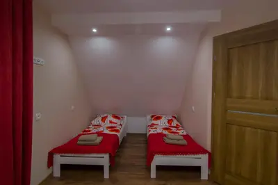 two beds in a small room with red sheets at Bacówka na Zadzielu in Laskowa