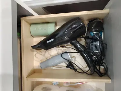 a black hairdryer and other items in a drawer at Apartament Mazowiecka 125 in Kraków