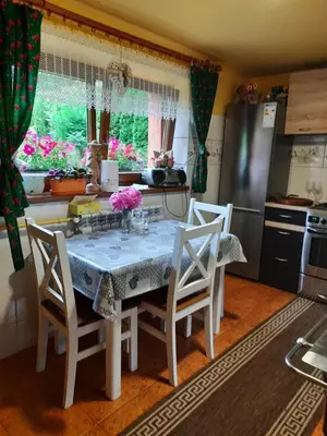 a kitchen with a table and chairs with flowers on it at Pokoje u Zajdy in Zawoja