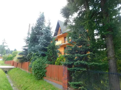 an orange house with a fence and trees at Pokoje u Zajdy in Zawoja