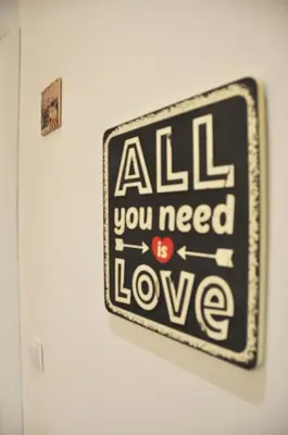 a sign that says all you need is love on a wall at Tenczyńska 4 by Homeprime in Kraków