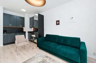 a living room with a green couch and a chair at Apartamenty Rakowicka WAWELOFTS in Kraków