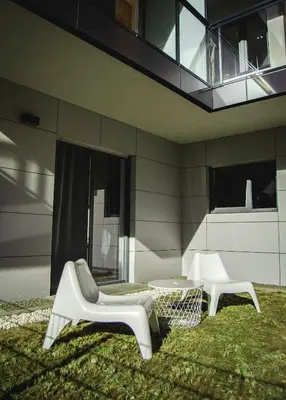two white chairs and a table in front of a building at Apartamenty Rakowicka WAWELOFTS in Kraków