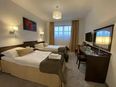 a hotel room with two beds and a desk at Hotel Tadeusz in Uszew